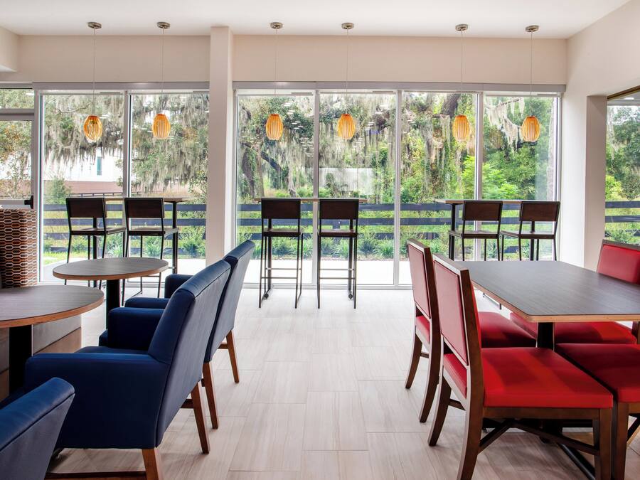 A modern dining area with large windows, wooden tables, and chairs.