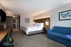 A hotel room with a bed, a desk with a chair, a sofa, and a TV. - Holiday Inn Express & Suites Deland South by IHG (DeLand)