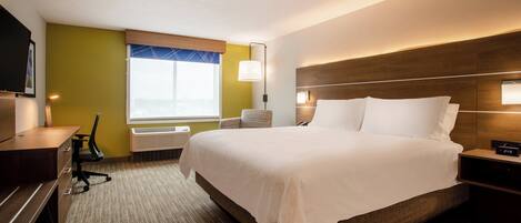 A hotel room with a large bed, bedside tables, a desk, and a chair.