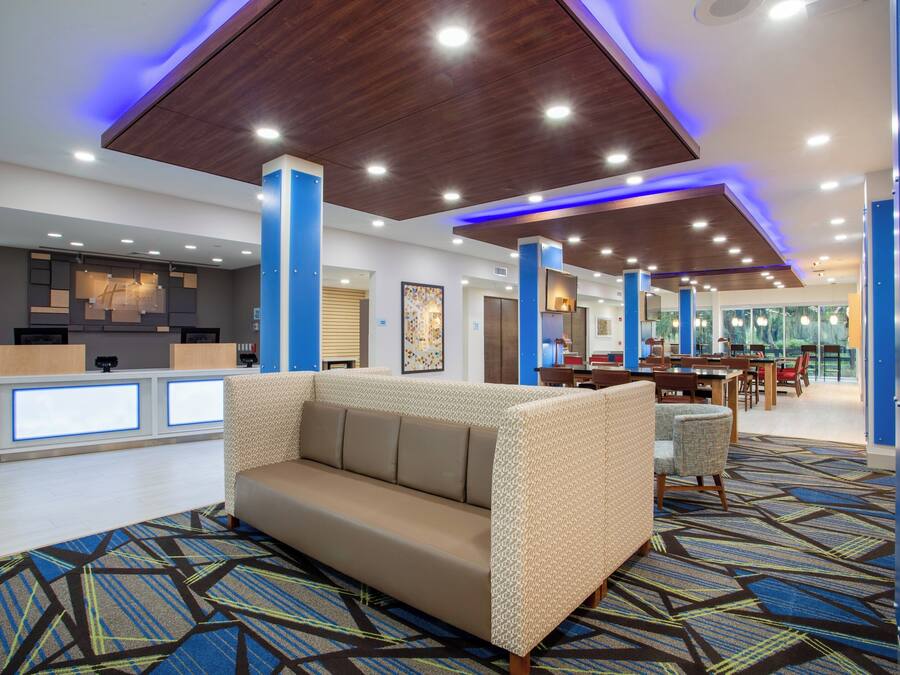 A modern hotel lobby with a reception desk, a sofa, and a dining area.