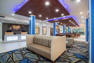 Un moderno vestíbulo de hotel con mostrador de recepción, un sofá y un comedor.