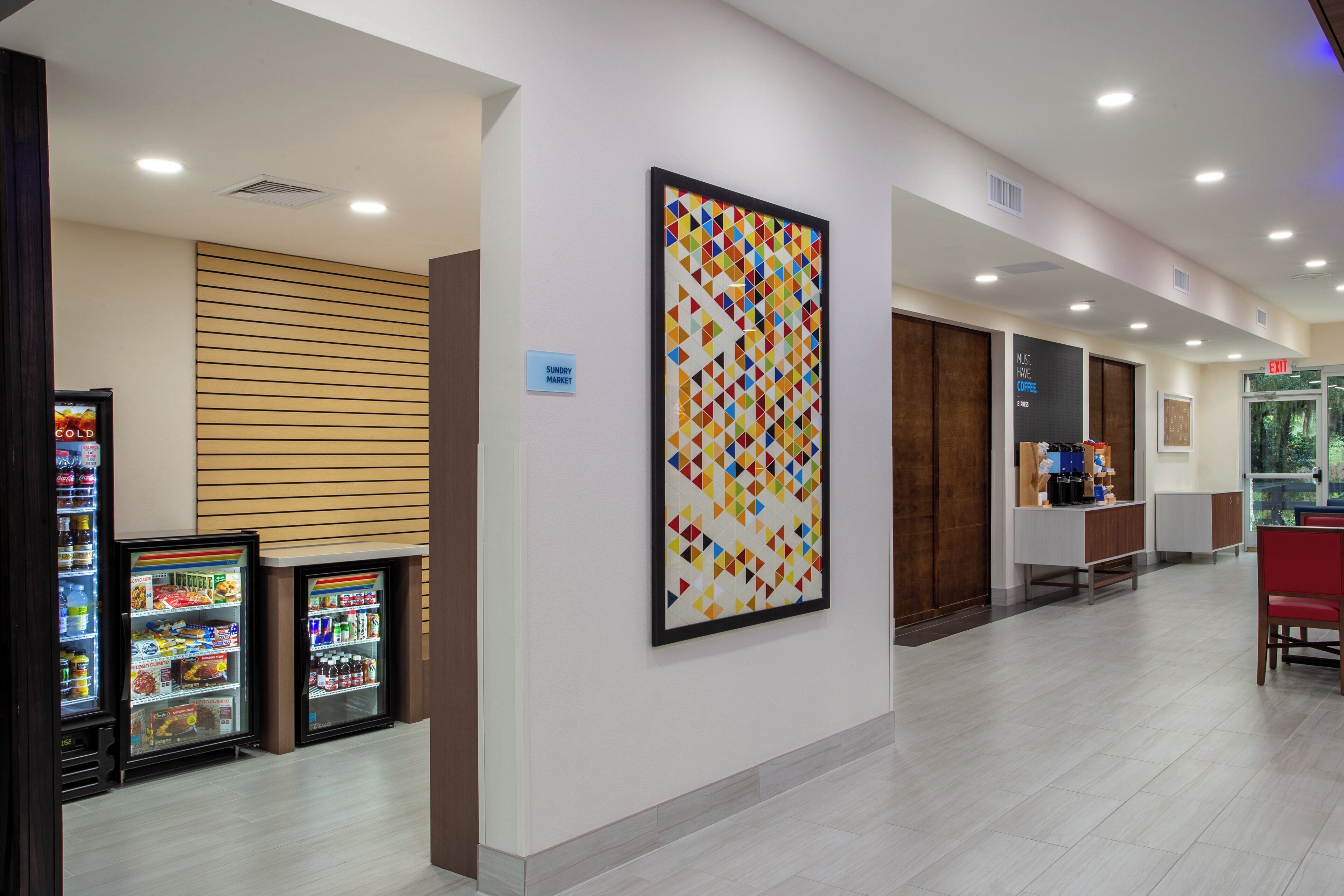 A hallway with vending machines, a wall-mounted artwork, and an exit sign.