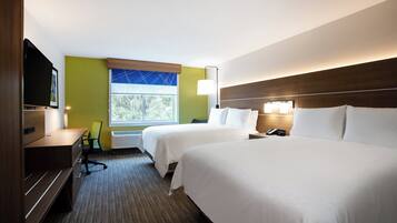 A hotel room with two beds, a desk, a chair, a TV, and a window with a view of trees.
