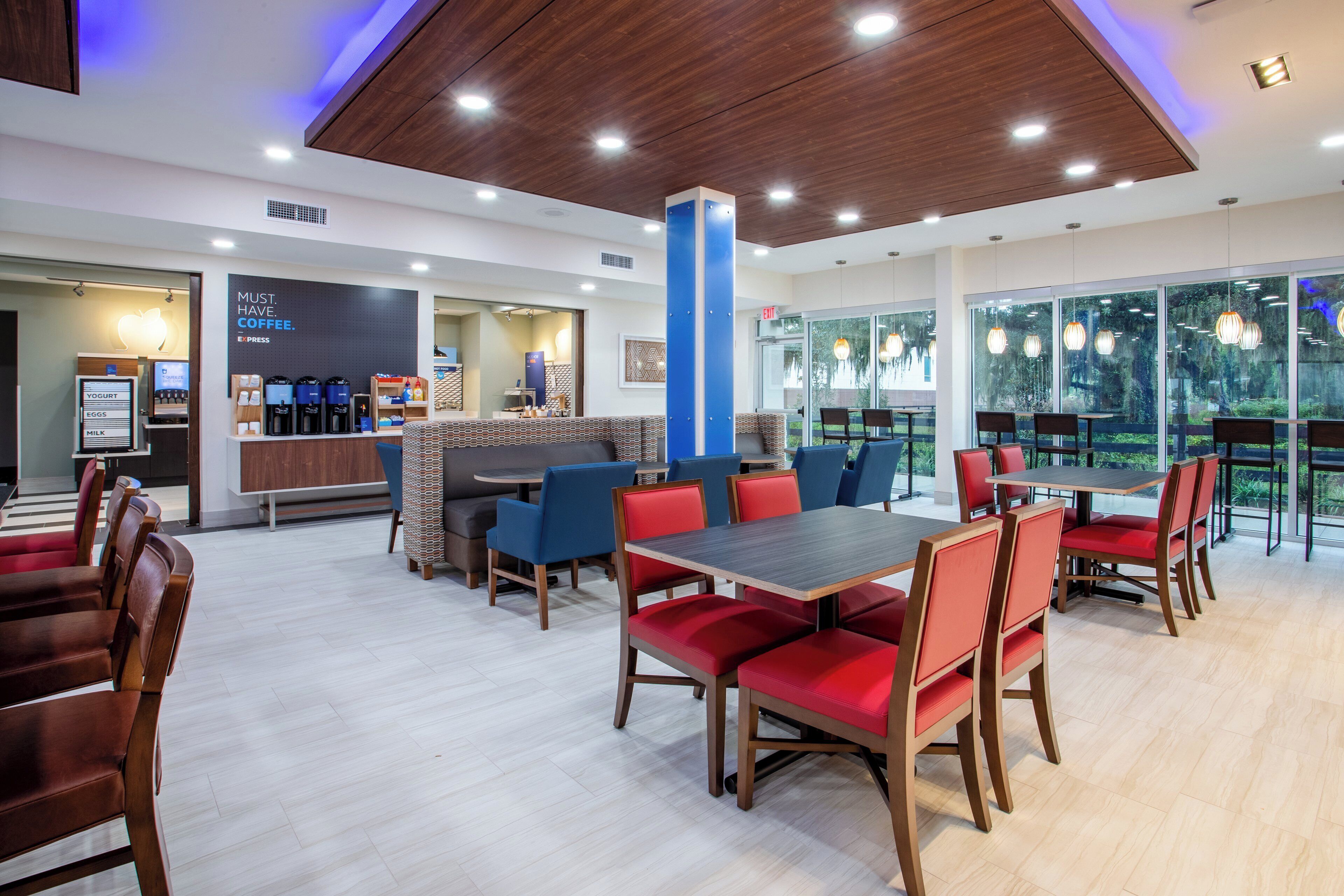 A modern cafe with a bar area, seating arrangements, and a view through large windows.