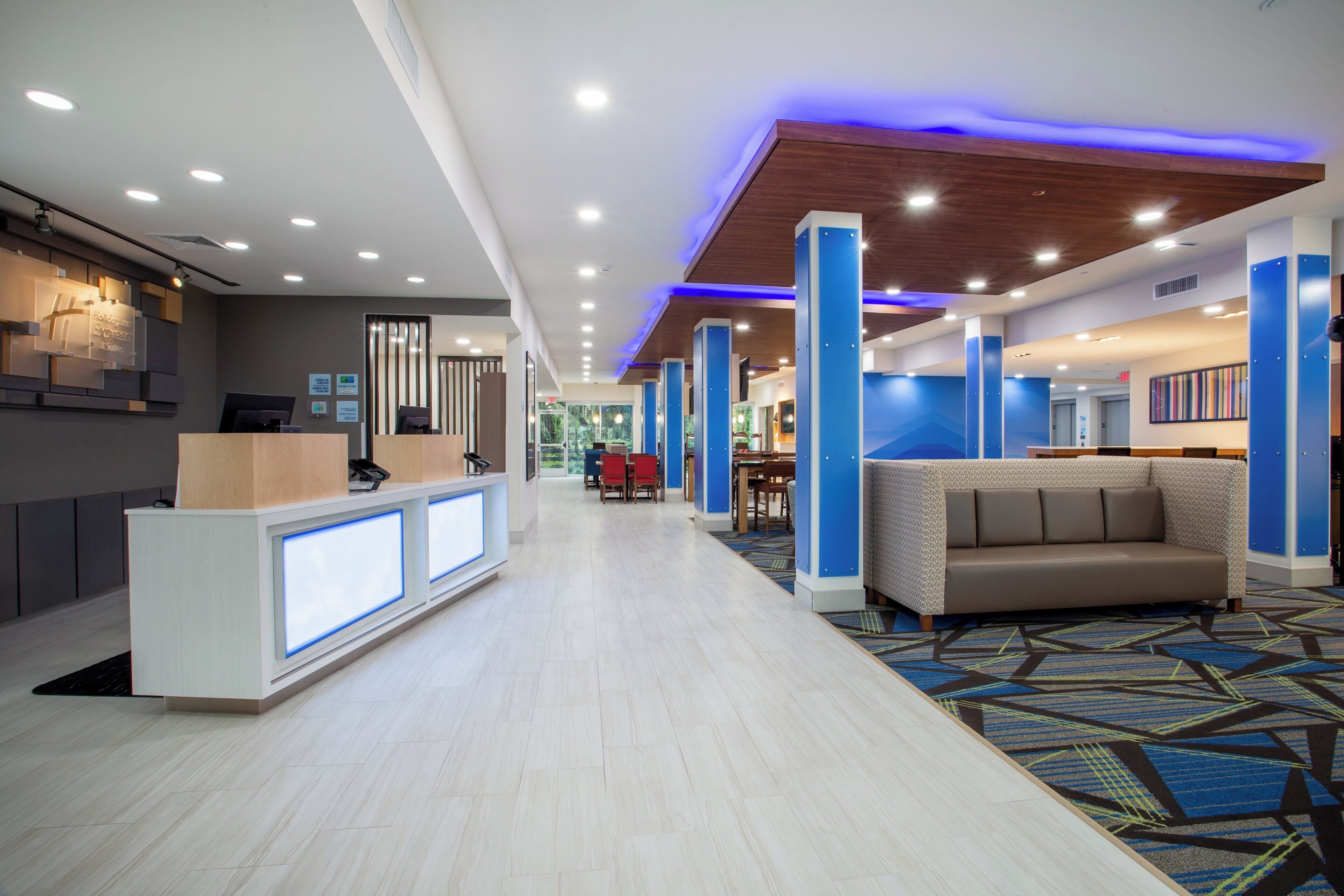 A hotel lobby with a reception desk, seating area, and a view of the outdoors.
