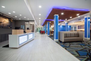A hotel lobby with a reception desk, seating area, and a view of the outdoors.