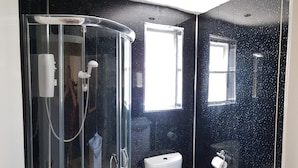 A bathroom with a glass-enclosed shower, a toilet, and a window. - Glen Villa Flat 1 - 4 Berth (Great Yarmouth)