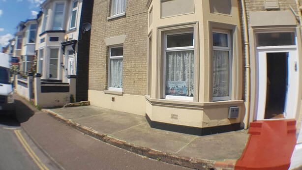 A row of terraced houses with bay windows, a clear blue sky, and a yellow double line on the road. - Glen Villa Flat 1 - 4 Berth (Great Yarmouth)