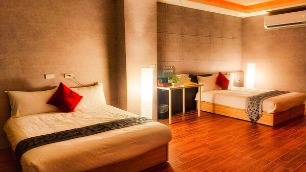 A hotel room with two beds, a small table, and a desk. - SUAO Backpackers (Suao)