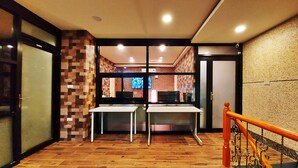 A hotel lobby with a tiled floor, a reception desk, a television screen, and a staircase with a wooden railing. - SUAO Backpackers (Suao)