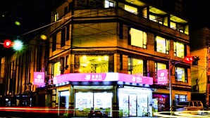A multi-story building with illuminated signage and windows, located at a street corner. - SUAO Backpackers (Suao)