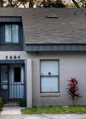 A building with the number 5684, a closed window with a metal shutter, and a small plant in the foreground.