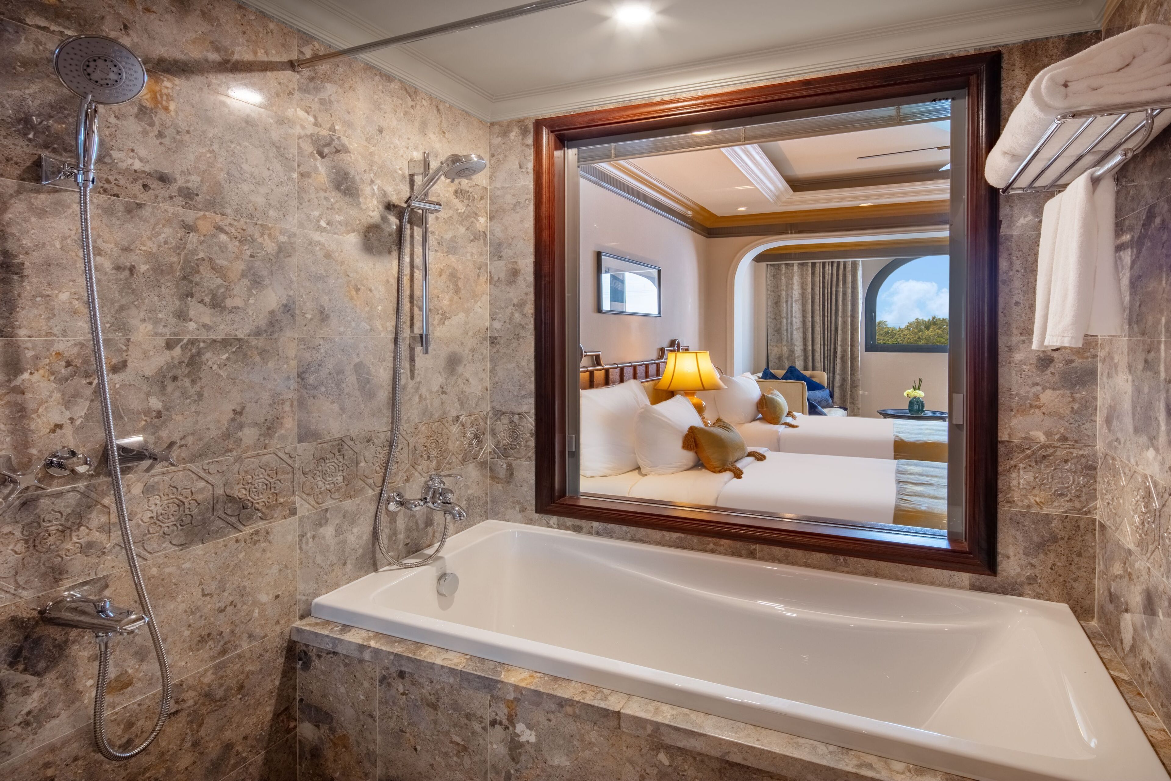 A bathroom with a bathtub, a shower, and a large mirror reflecting the room.