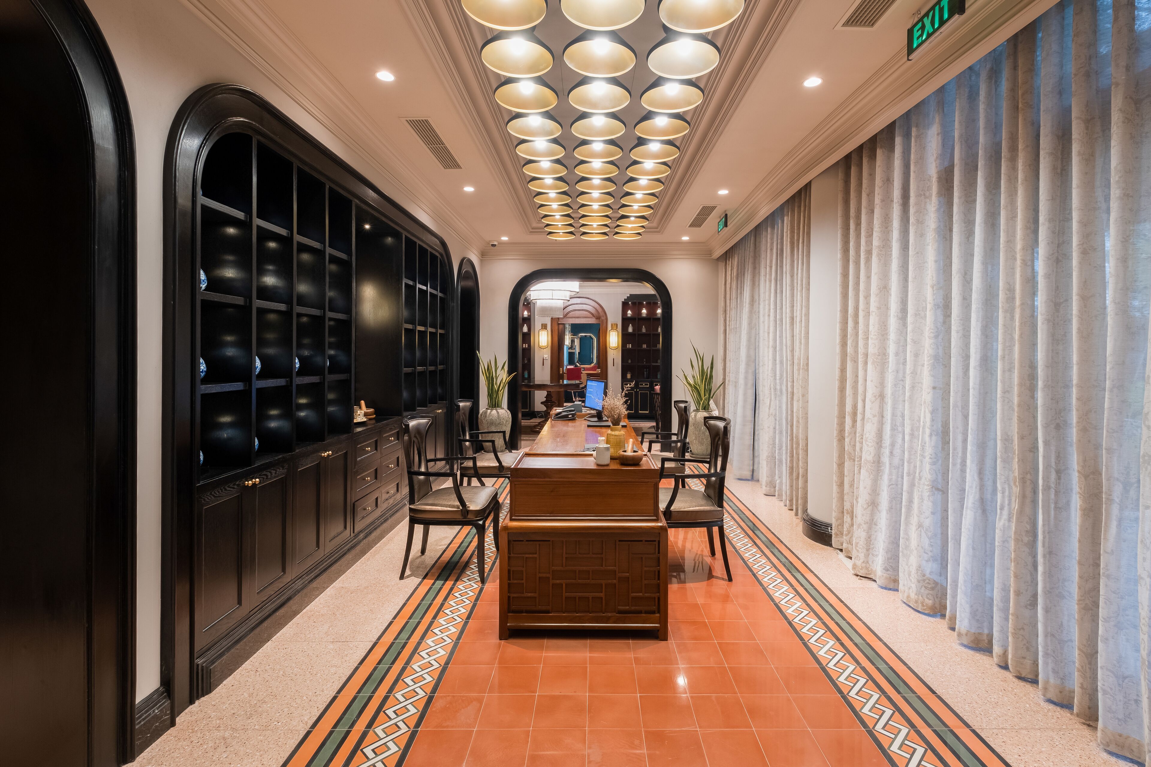 A hotel lobby with a reception desk, seating area, and a patterned floor.