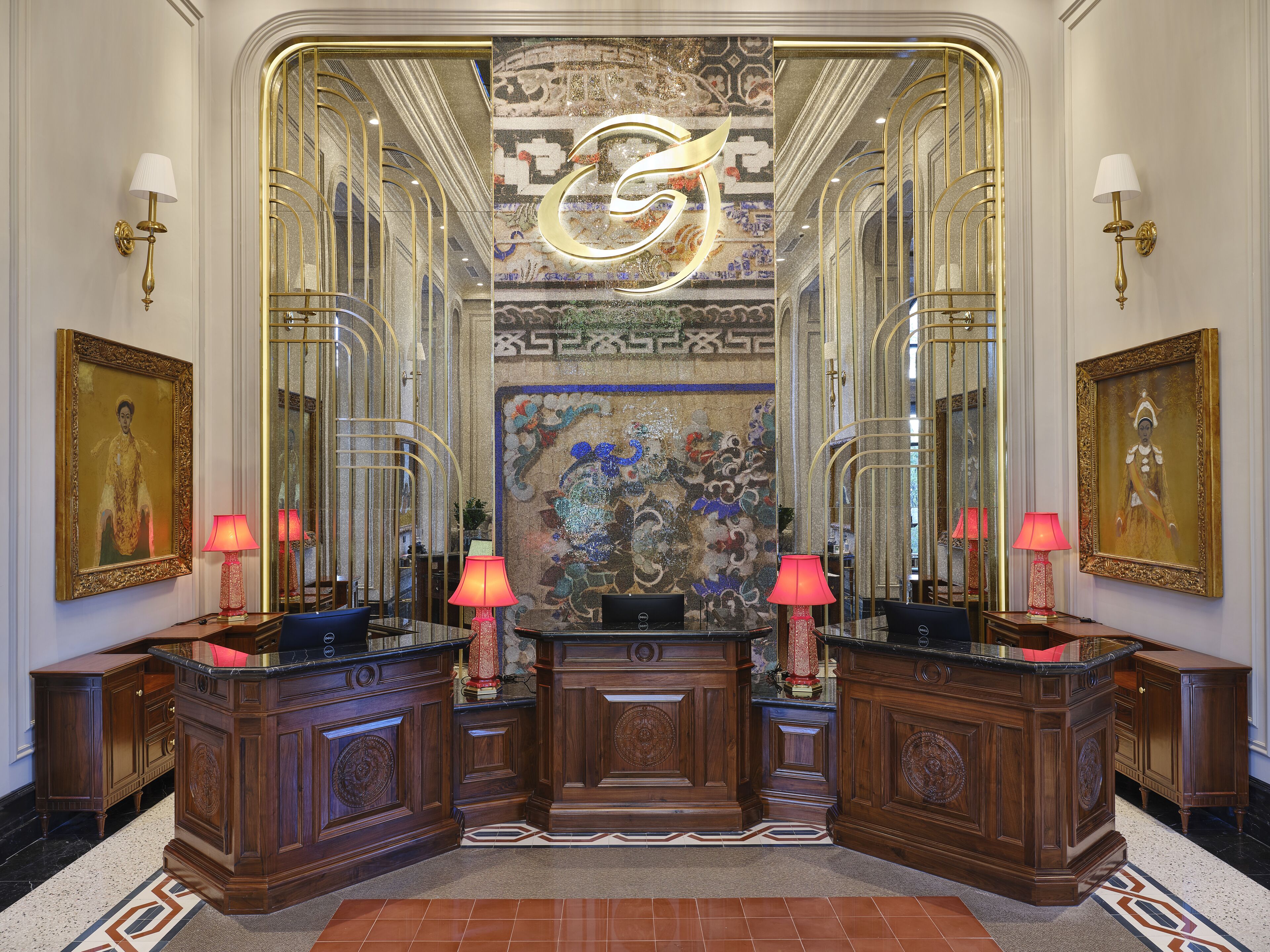 A luxurious lobby with ornate wood paneling, a central decorative wall, and two side tables with lamps.