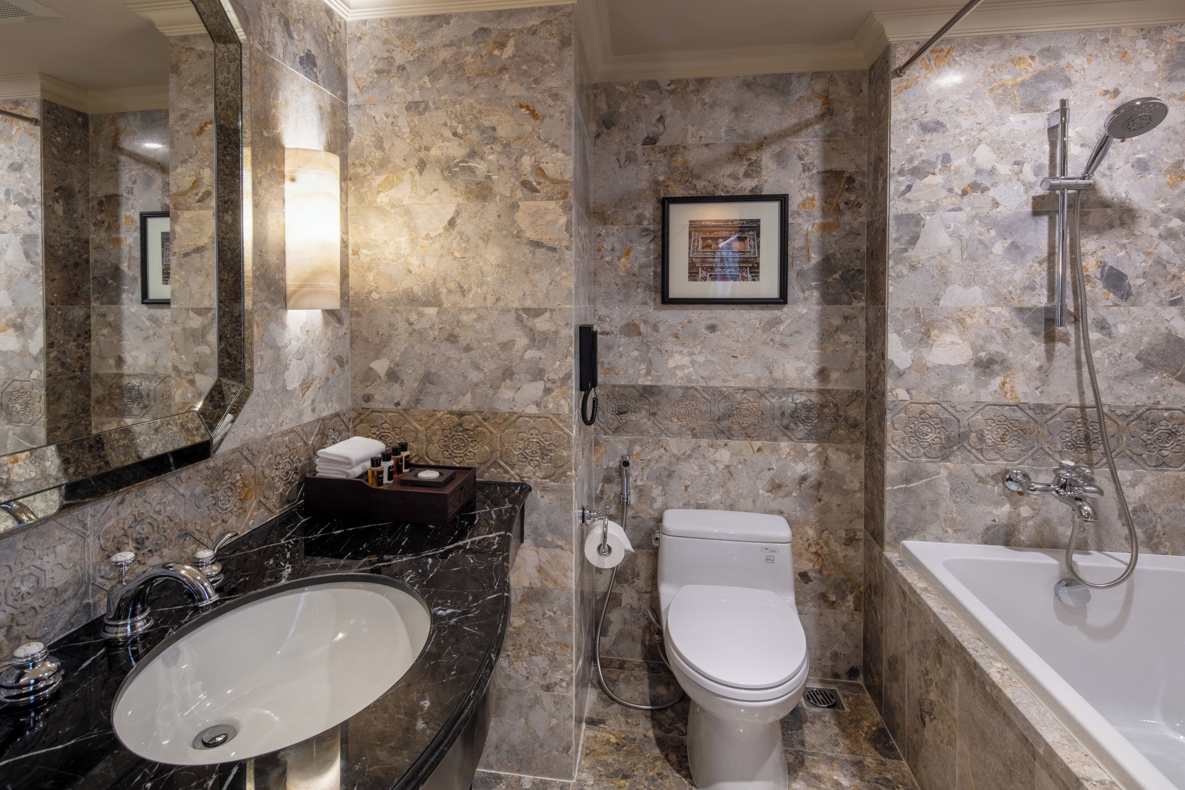 Un baño con lavamanos, inodoro y bañera de mármol.