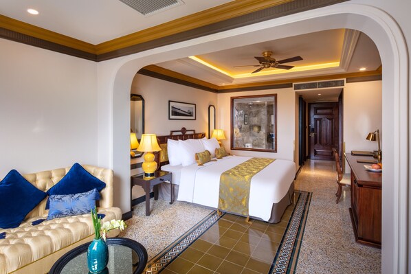 A hotel room with a bed, a sofa, a desk, and a chair.