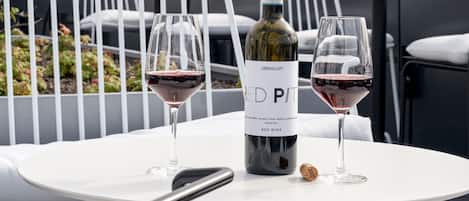 A table with two wine glasses and a bottle of wine on a rooftop terrace with a view of a church spire.