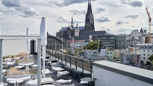 Une terrasse sur le toit, dotée d’un espace extérieur aménagé et offrant une vue sur une cathédrale historique.