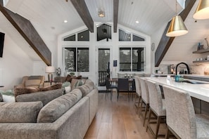 A spacious living area with a large sofa, a dining table with chairs, and a kitchen area with a bar.