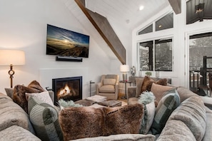 A cozy living room with a fireplace, comfortable seating, and a large window.