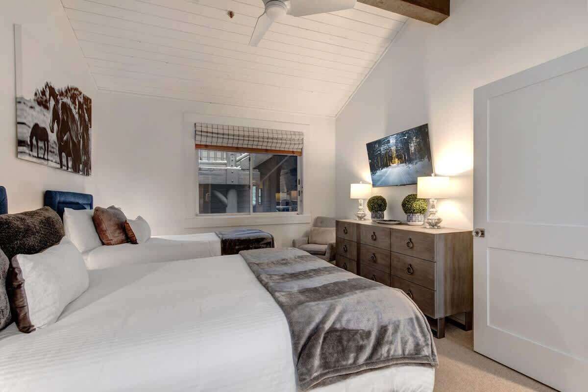 A bedroom with a large bed, a dresser, a nightstand, and a window.