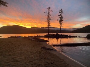 A beach with a sunset, a calm lake, and a small dock. - Camp Sammy-Rocky Manor (Hadley)