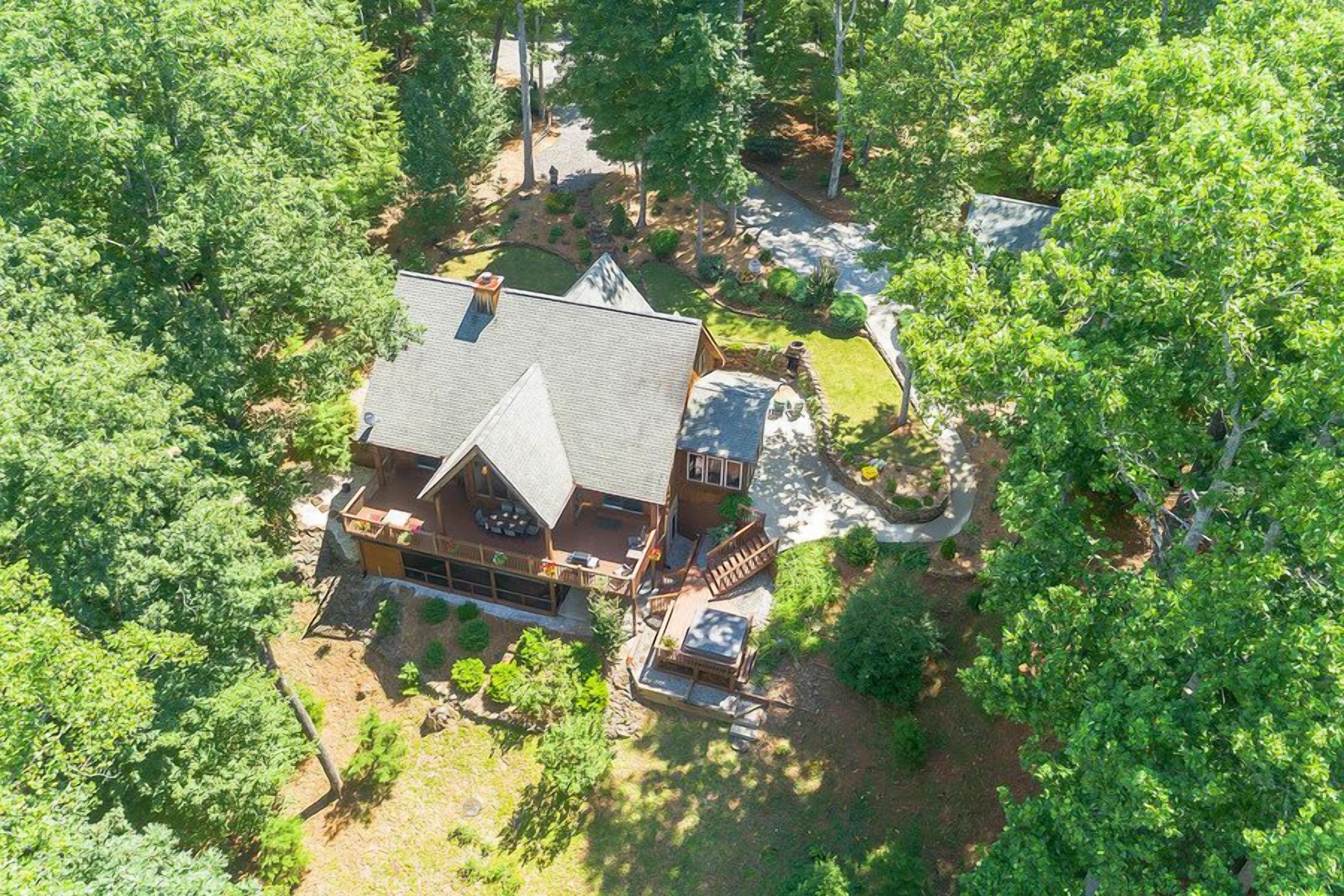 An aerial view of a log cabin with a large deck and a covered outdoor seating area.