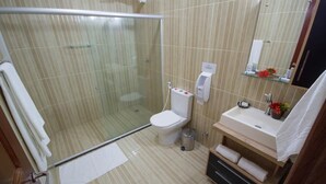 Un baño moderno con ducha envuelta en vidrio, inodoro, lavabo y espejo.