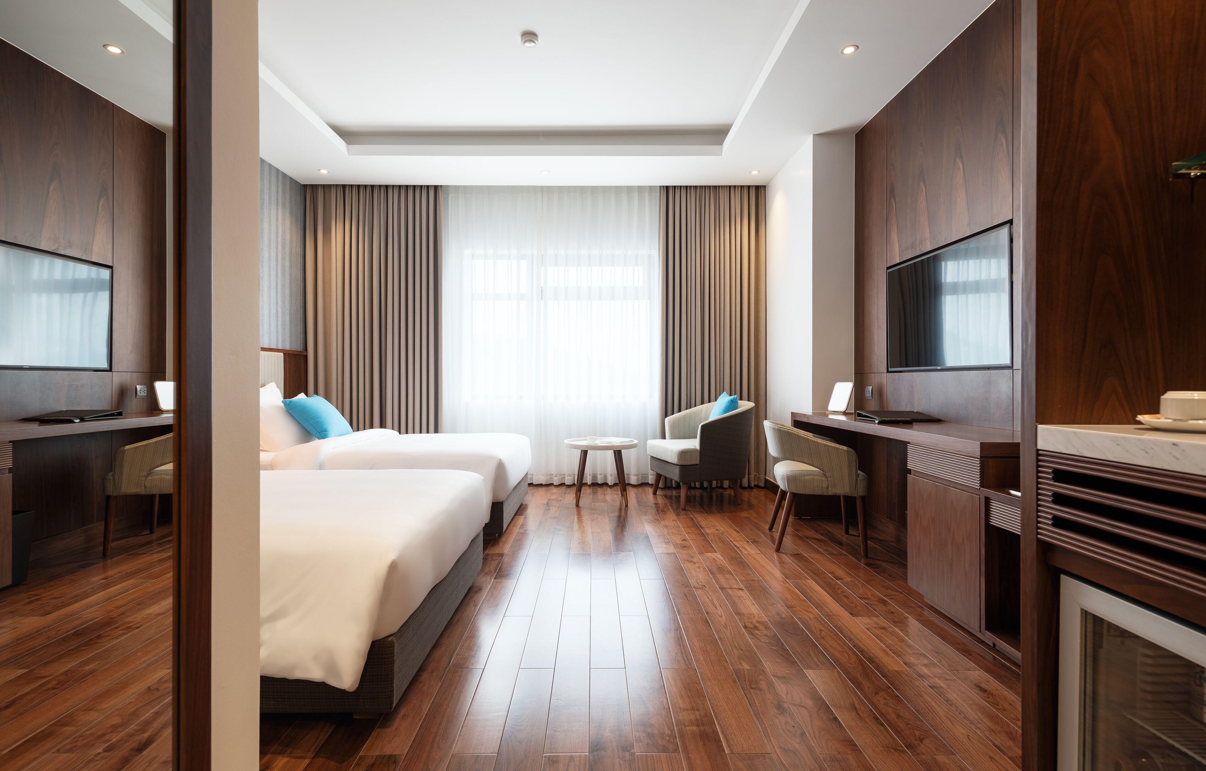 A hotel room with a large bed, a desk, a chair, a TV, and a fireplace.