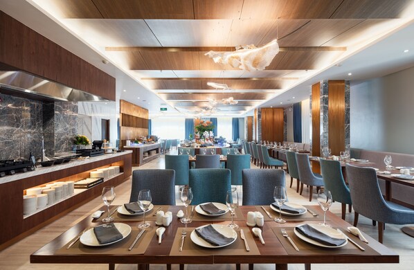 Un espace repas moderne avec une longue table dressée pour un repas, entourée de chaises.