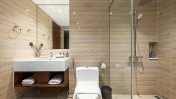 A modern bathroom with a glass-enclosed shower, a wooden vanity, and a marble-tiled wall.