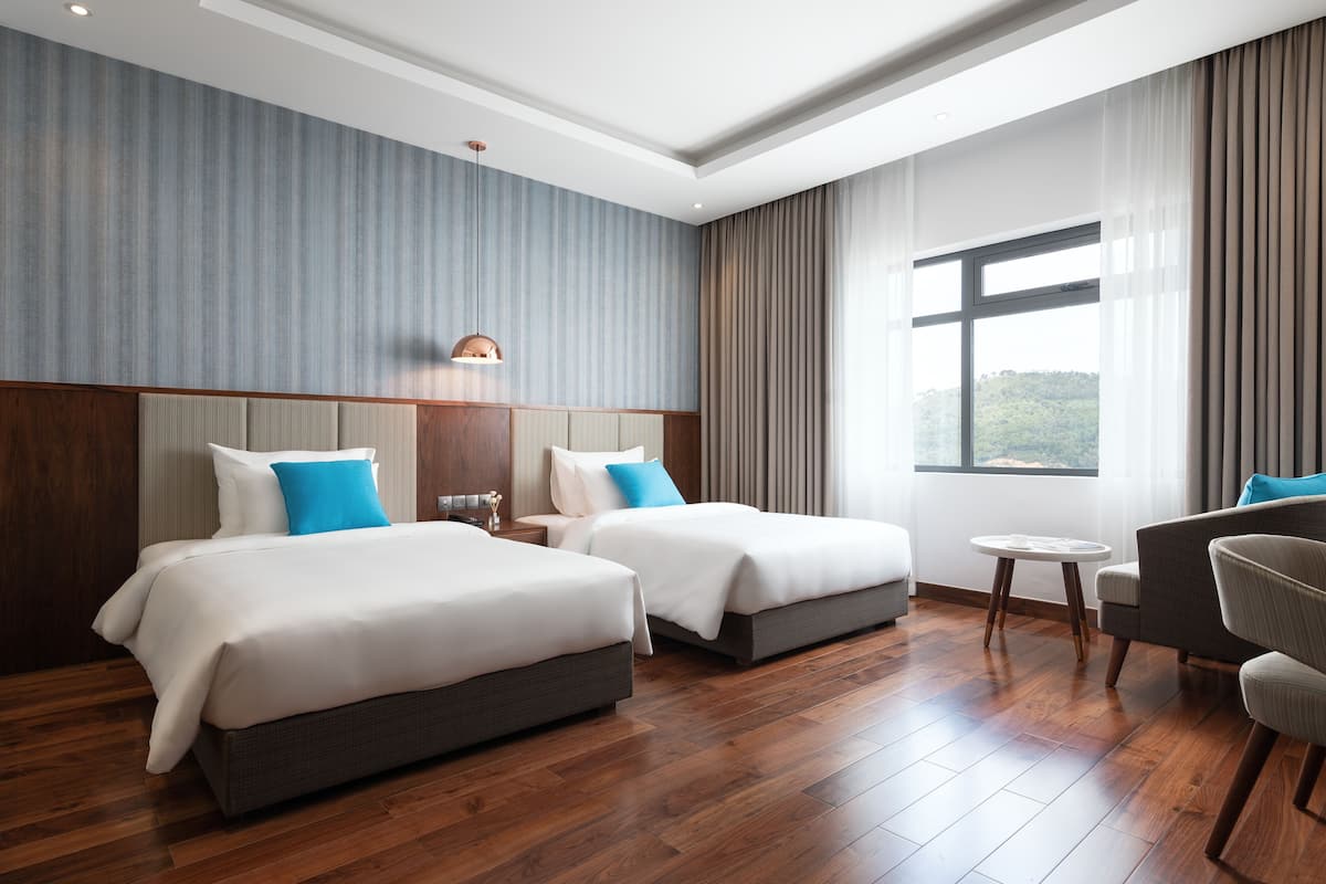 A hotel room with two beds, a small table, and a sofa.