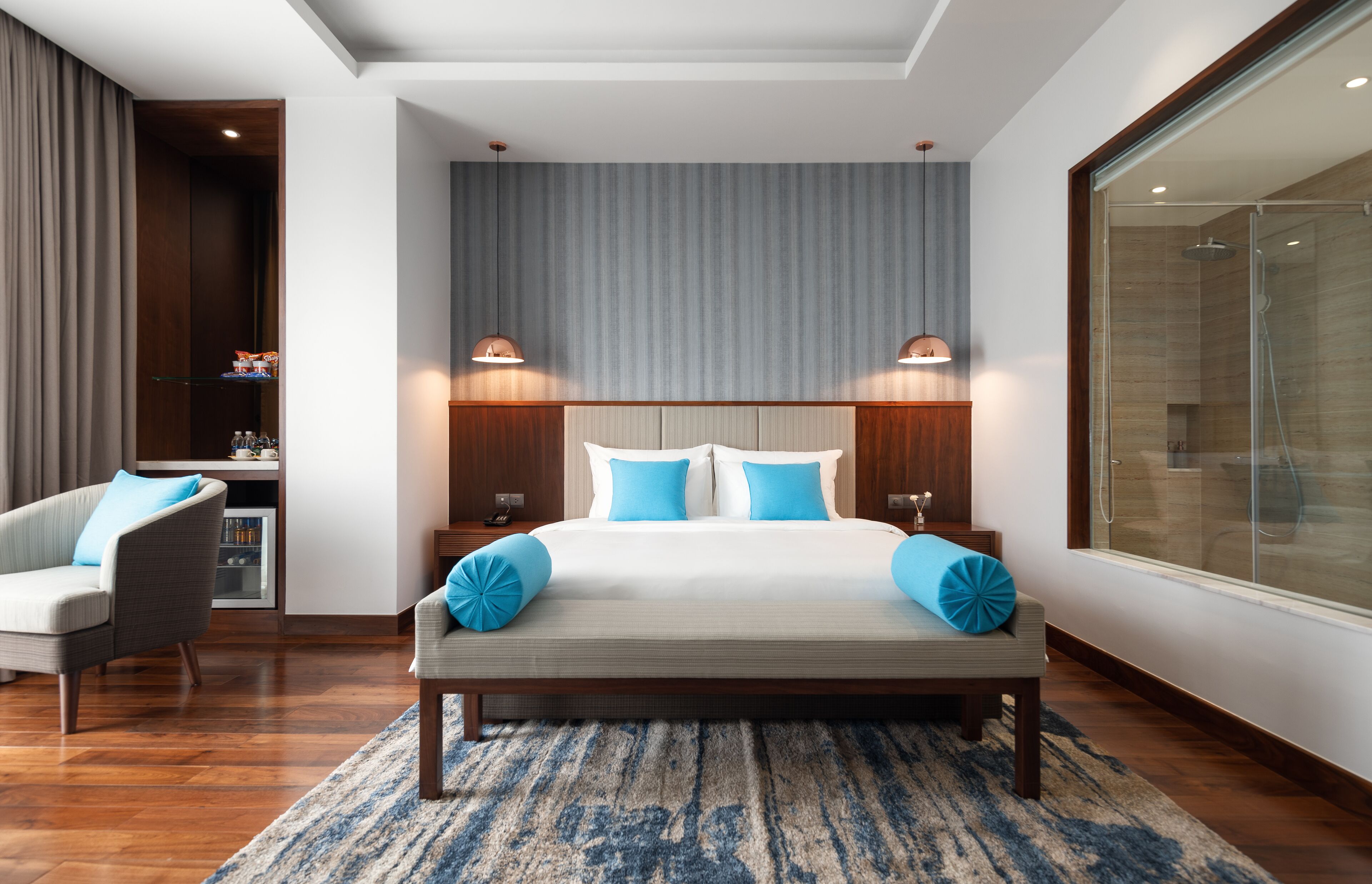 A modern bedroom with a large bed, two bedside tables, a nightstand, a chair, and a large window.