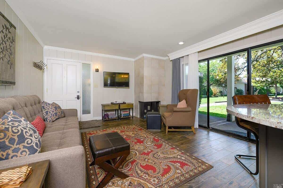 A spacious living room with a large window, a sofa, a coffee table, and a fireplace.