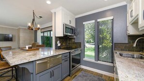 A modern kitchen with a large island, built-in oven, and a dining area with bar stools.