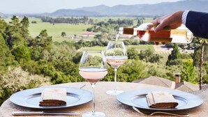 A table set with plates, glasses, and a bottle being poured into one of the glasses.