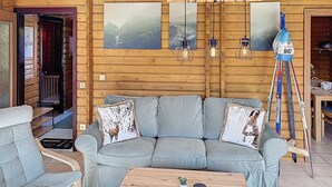 A log cabin interior with a grey sofa, wooden coffee table, and framed pictures on the wall. - Franzi 2 by Interhome (Arrach)