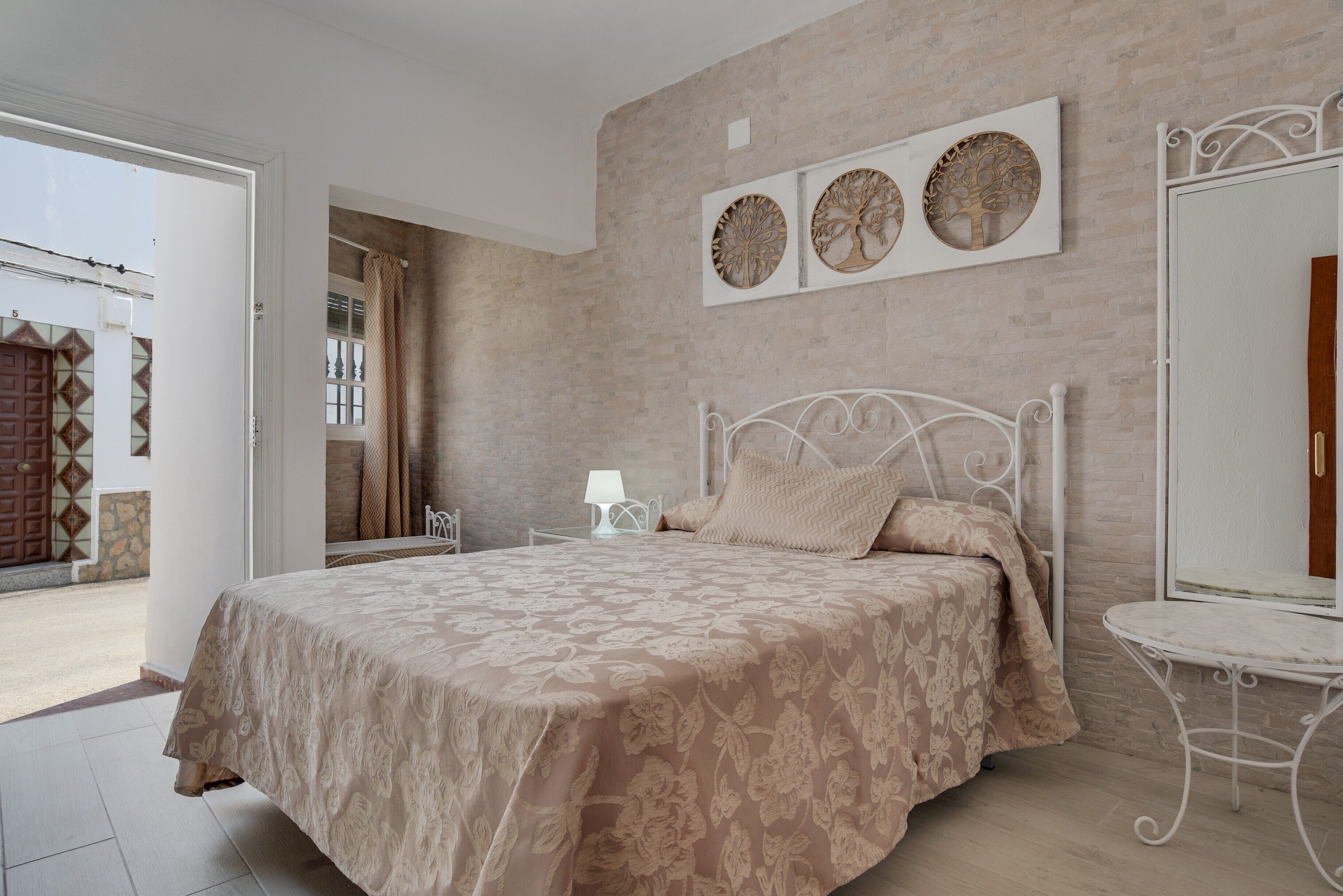 Une chambre à coucher avec un lit, une table de chevet, une lampe et un miroir fixé au mur.