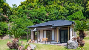 A modern house with a covered patio, a bench, and a large rock. - Sasayakana Ouchi Fuuki (Futtsu)