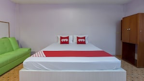 A bedroom with a bed, a green sofa, and a wooden wardrobe. - OYO 1070 Paradise Resort (Ban Chang)