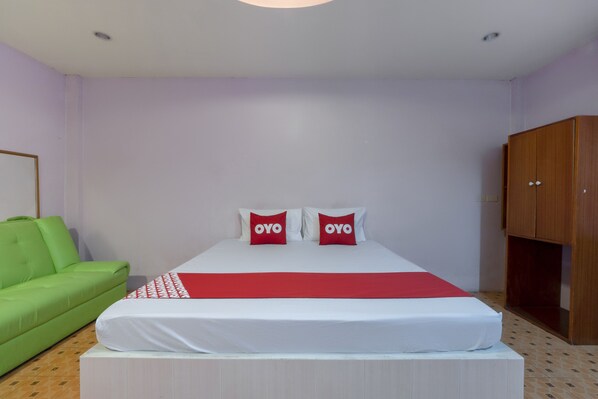 A bedroom with a bed, a green sofa, and a wooden wardrobe. - OYO 1070 Paradise Resort (Ban Chang)