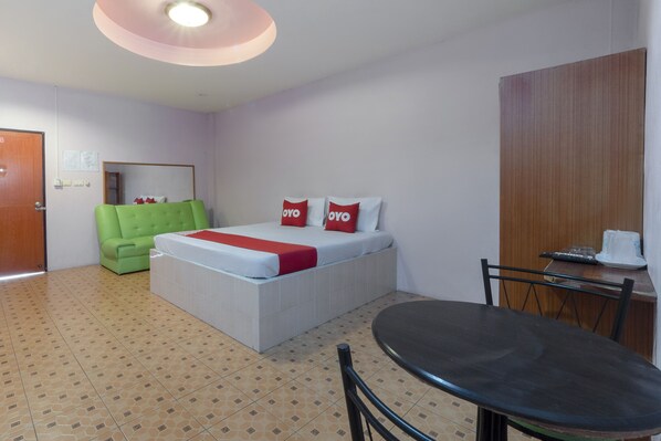 Une chambre d’hôtel avec un lit, un fauteuil vert et une table à manger.