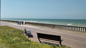 Ein Küstenweg mit Bänken und einer Brüstung, der auf das Meer hinausführt.