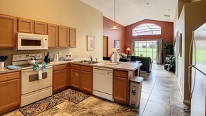A kitchen with wooden cabinets, a microwave, a stove, and a sink. - Emerald Island Resort 4 bed 3 bath with pool/spa (Kissimmee)
