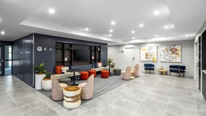 Un moderno vestíbulo de hotel con una zona de estar, un televisor de pantalla plana y obras de arte en las paredes.