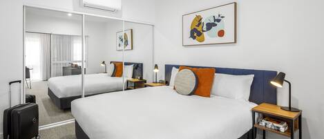 Habitación de hotel con una cama grande, una mesita de noche con lámpara, un espejo y un cuadro en la pared.