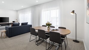 Una sala moderna con un sofá, una mesa de comedor, sillas y un televisor.