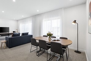 Una sala moderna con un sofá, una mesa de comedor, sillas y un televisor.