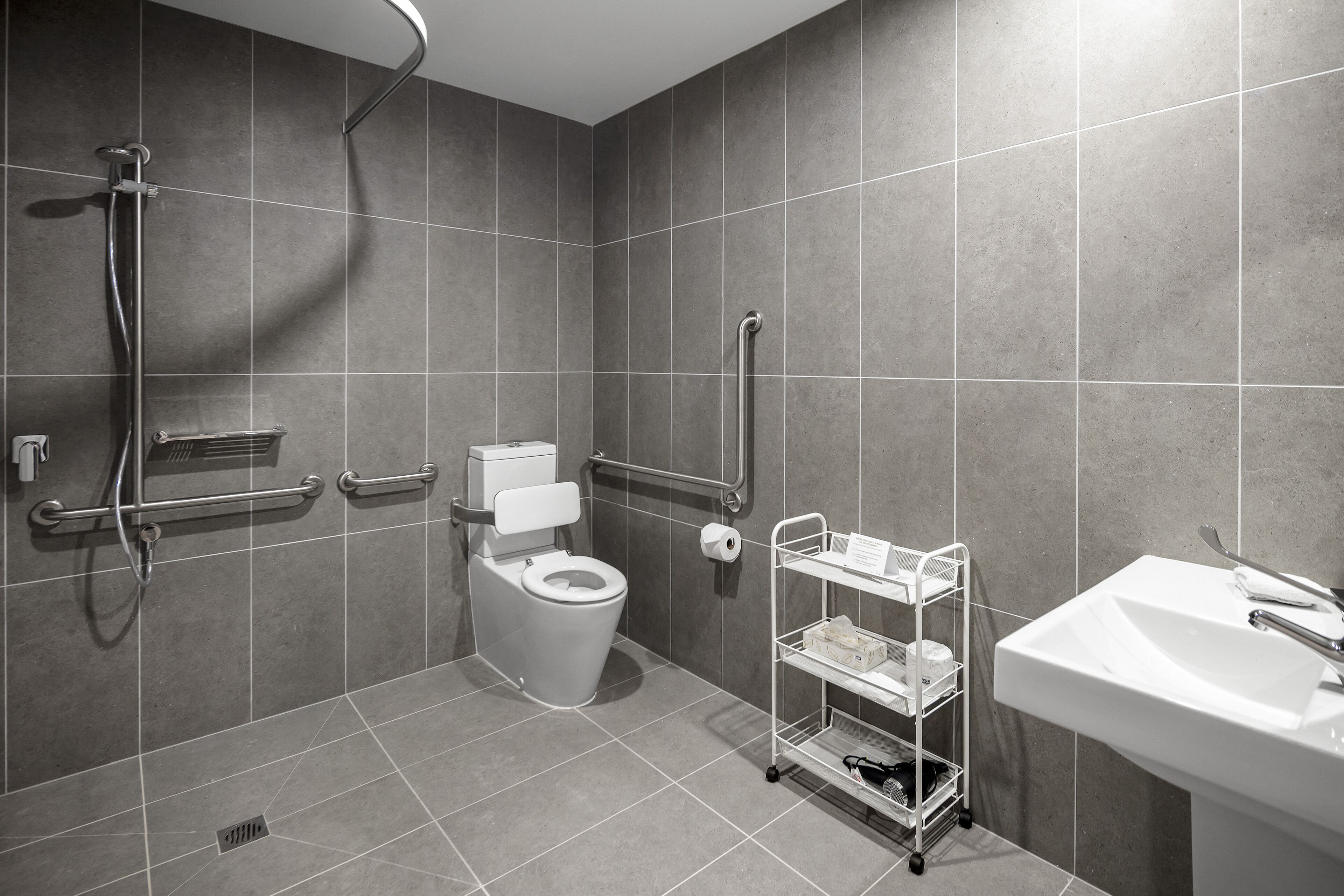 A modern bathroom with a shower, toilet, and sink.